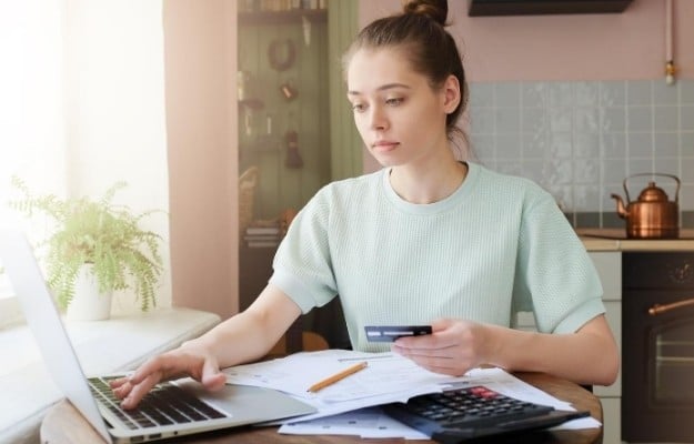 woman holding card and typing on computer ca